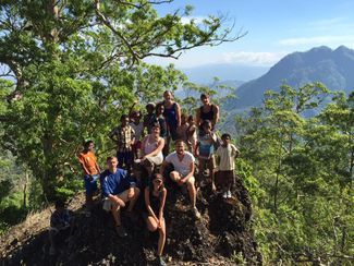 Group of students sitting on a cliff in a mountain forest of Timor-Leste